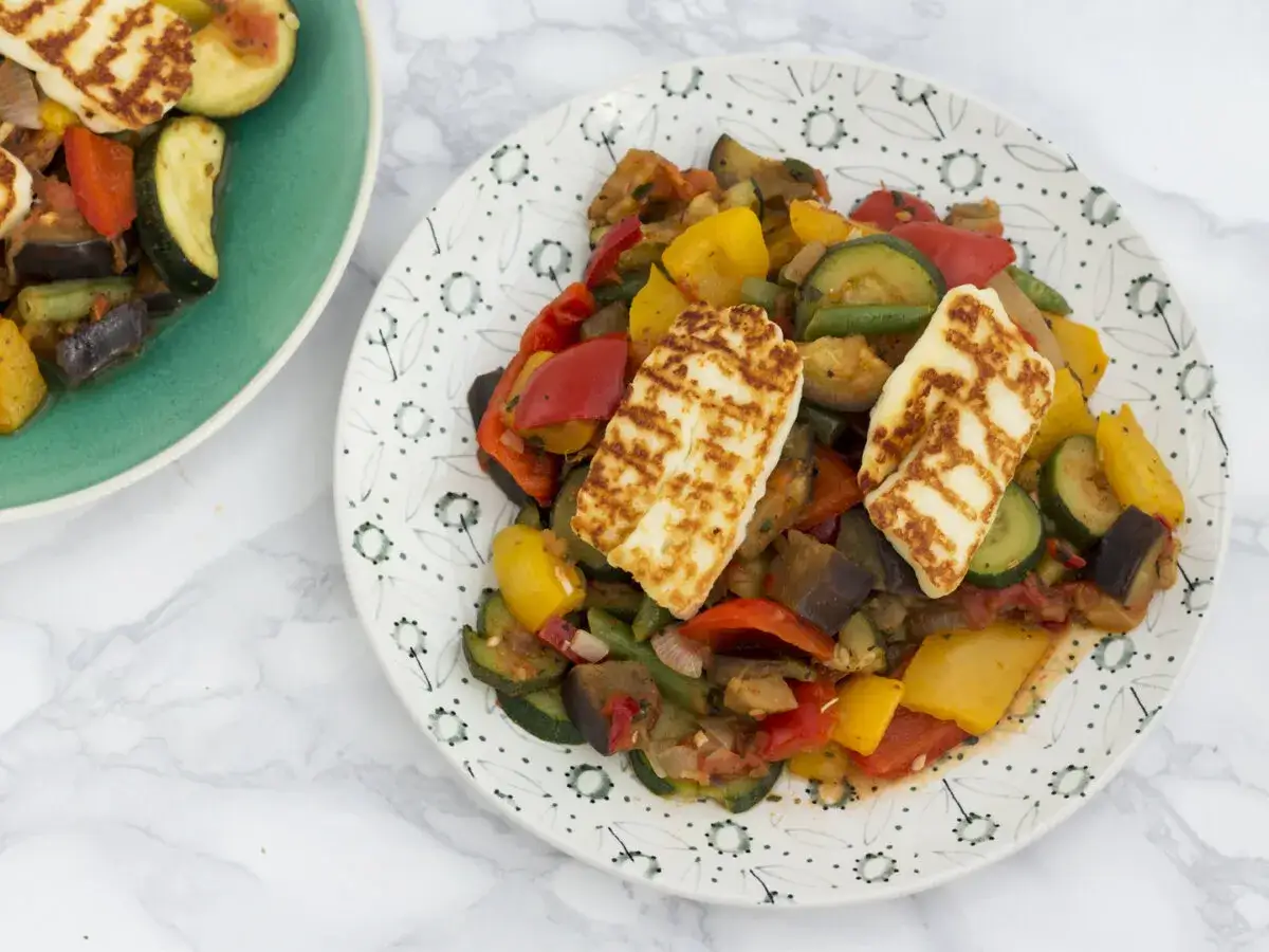Pyszne danie z grillowanymi warzywami i chrupiącym halloumi z grilla. Kolorowe papryki, cukinia i bakłażan tworzą apetyczną kompozycję.
