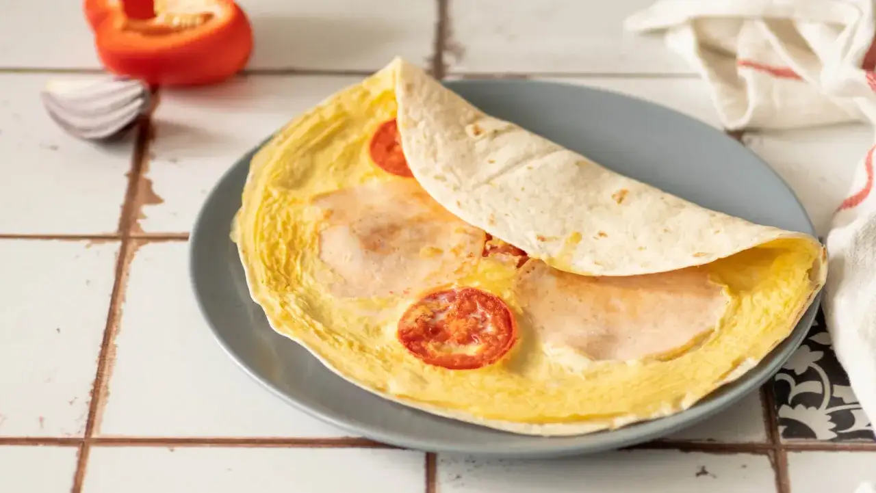 Tortilla z jajkiem, serem i szynką na patelni, z pomidorkami. Pyszne śniadanie gotowe w kilka minut.