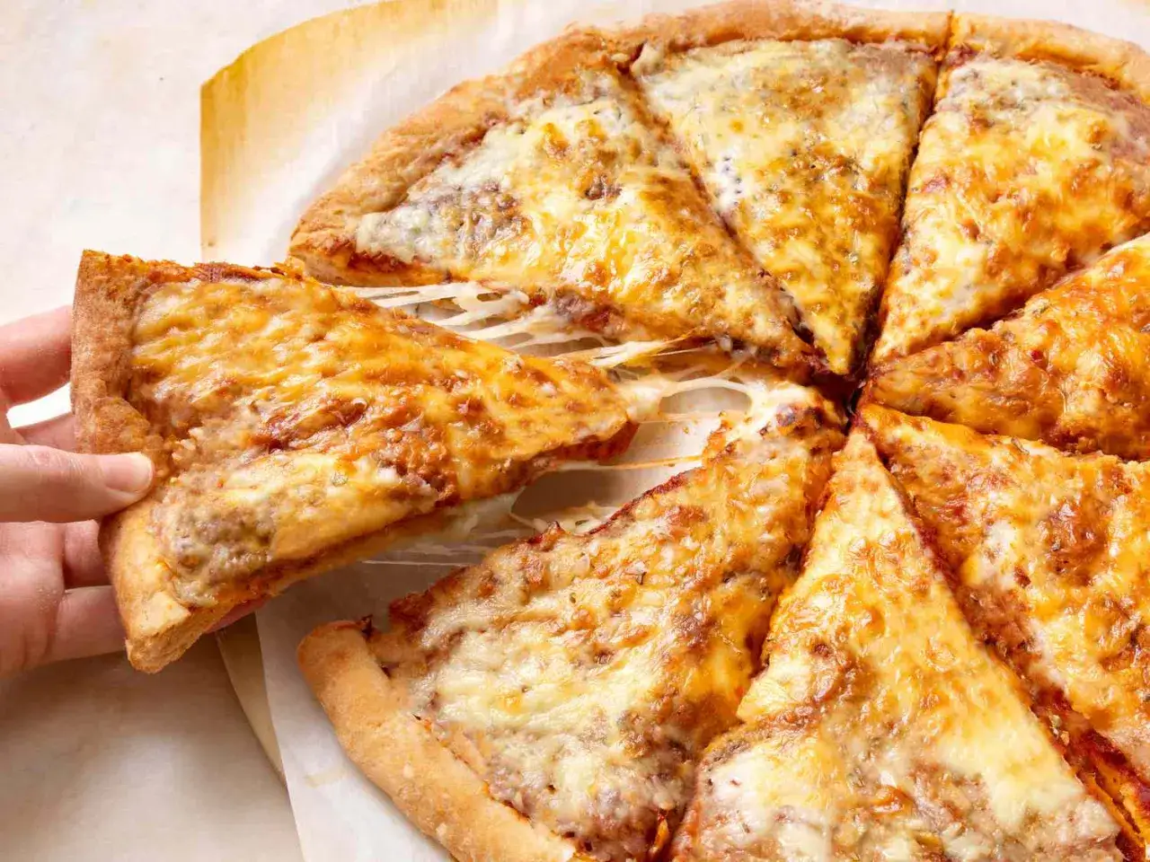 Pyszna pizza z ciągnącym serem, idealna na to, co zrobić z ciasta na pizzę. Ktoś podnosi kawałek.
