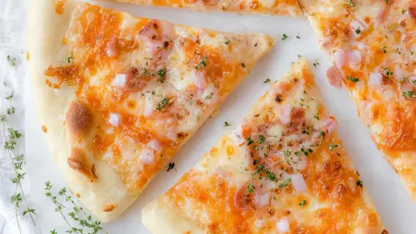 Kawałki pysznej pizzy z twarogu, posypane ziołami i kawałkami cebuli.